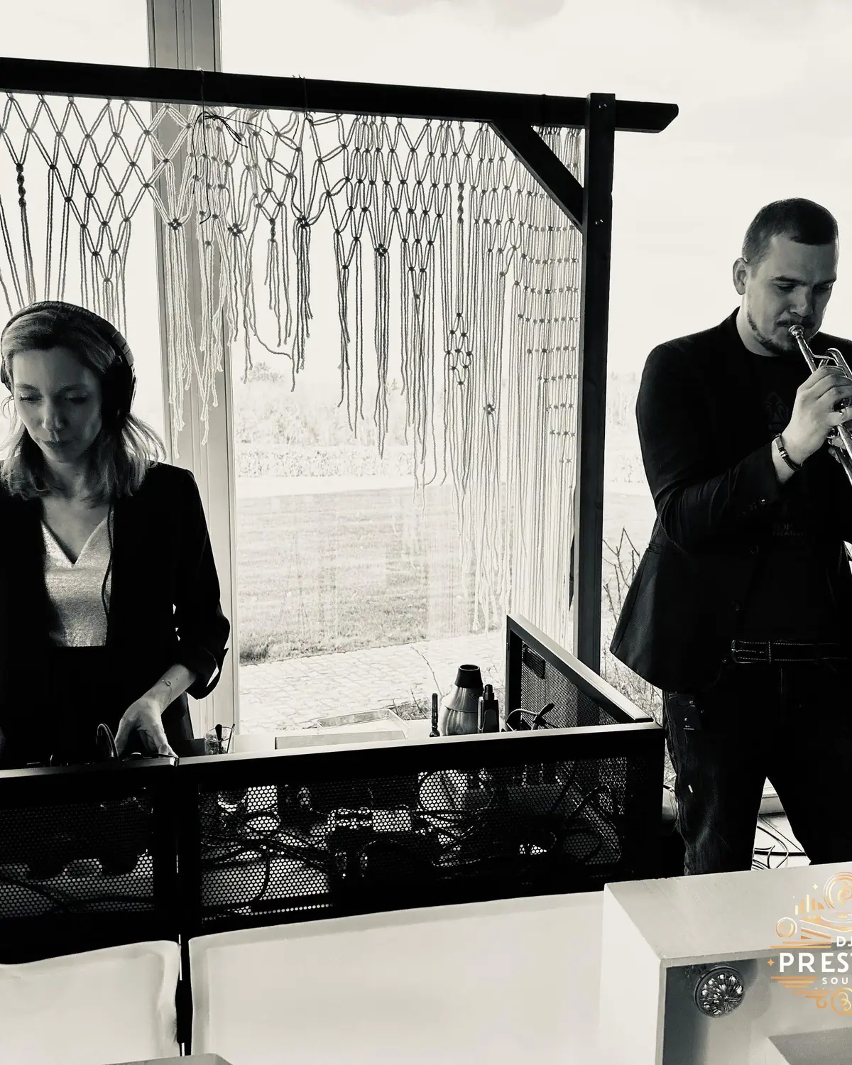 Un DJ aux platines et un trompettiste en costume, en noir et blanc