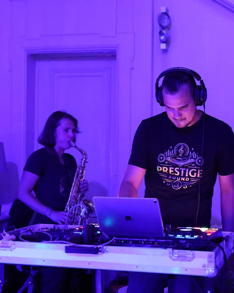 De DJ en de saxofoniste van Prestige Sound naast elkaar achter de mengtafel, onder paars licht (foto Vally Photography)