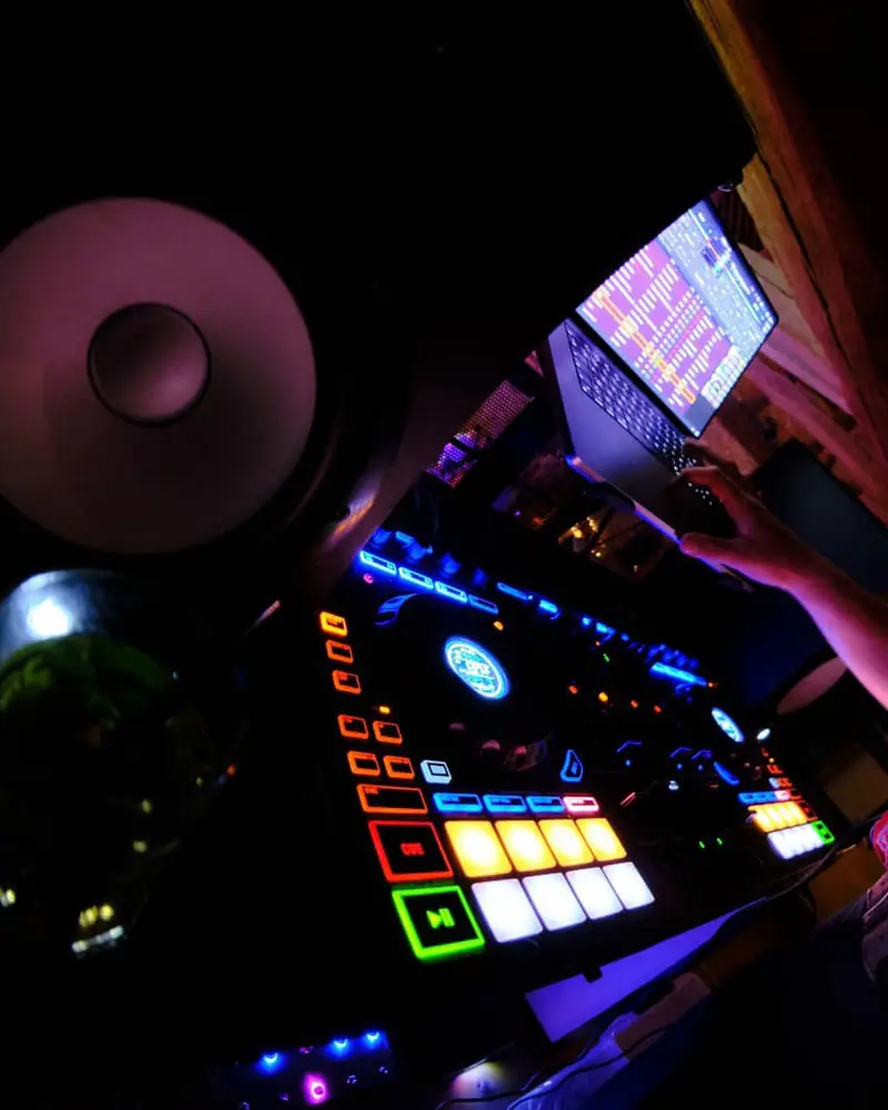 Een DJ-controller met verlichte pads, in het halfduister van een feest