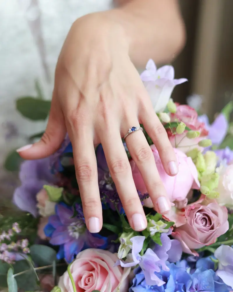 A hand wearing a ring above a bouquet of roses and hydrangeas (photo Vally Photography)