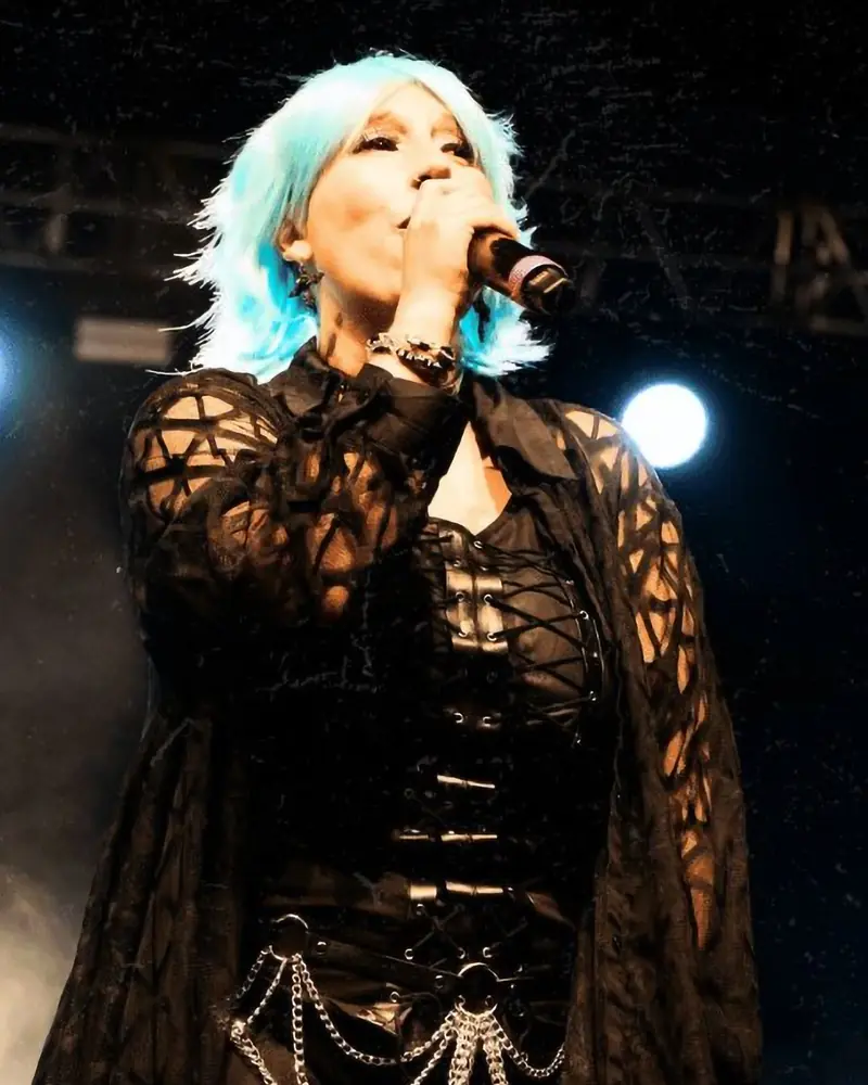 Mina Blue op het podium, microfoon in de hand, blauw haar (foto uit haar persmap)