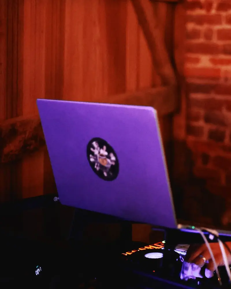 De laptop en controller van een DJ-booth, in een zaal met bakstenen muren