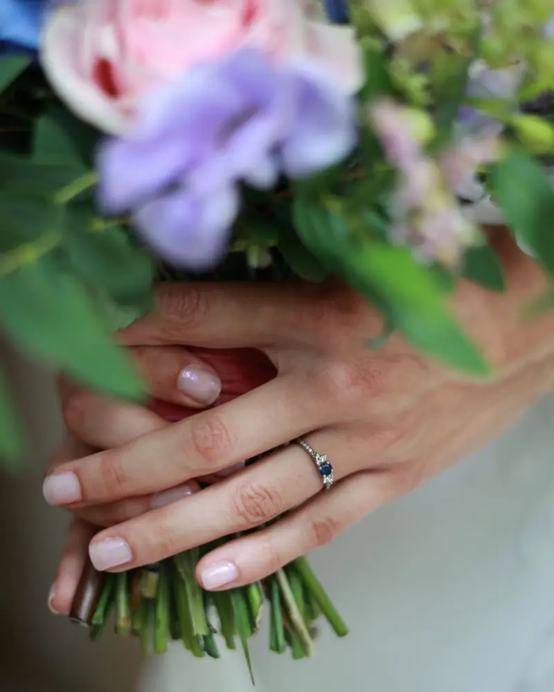 Des mains croisées sur un bouquet de roses et d'hortensias, une bague au doigt (photo Vally Photography)