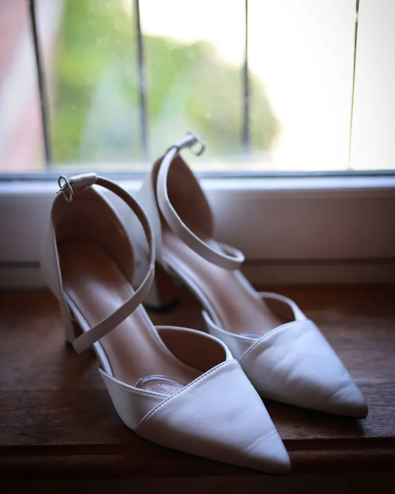 A pair of white heels on a window sill (photo by Vally Photography)