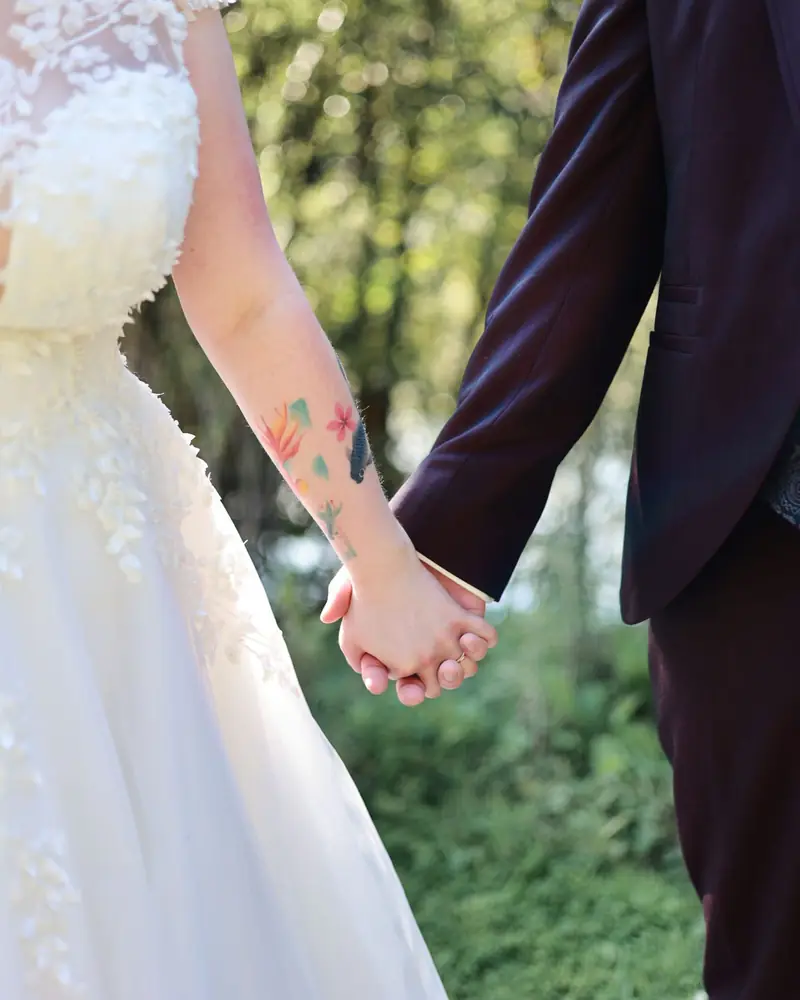 Le couple main dans la main, en tenue de mariage (photo Vally Photography)