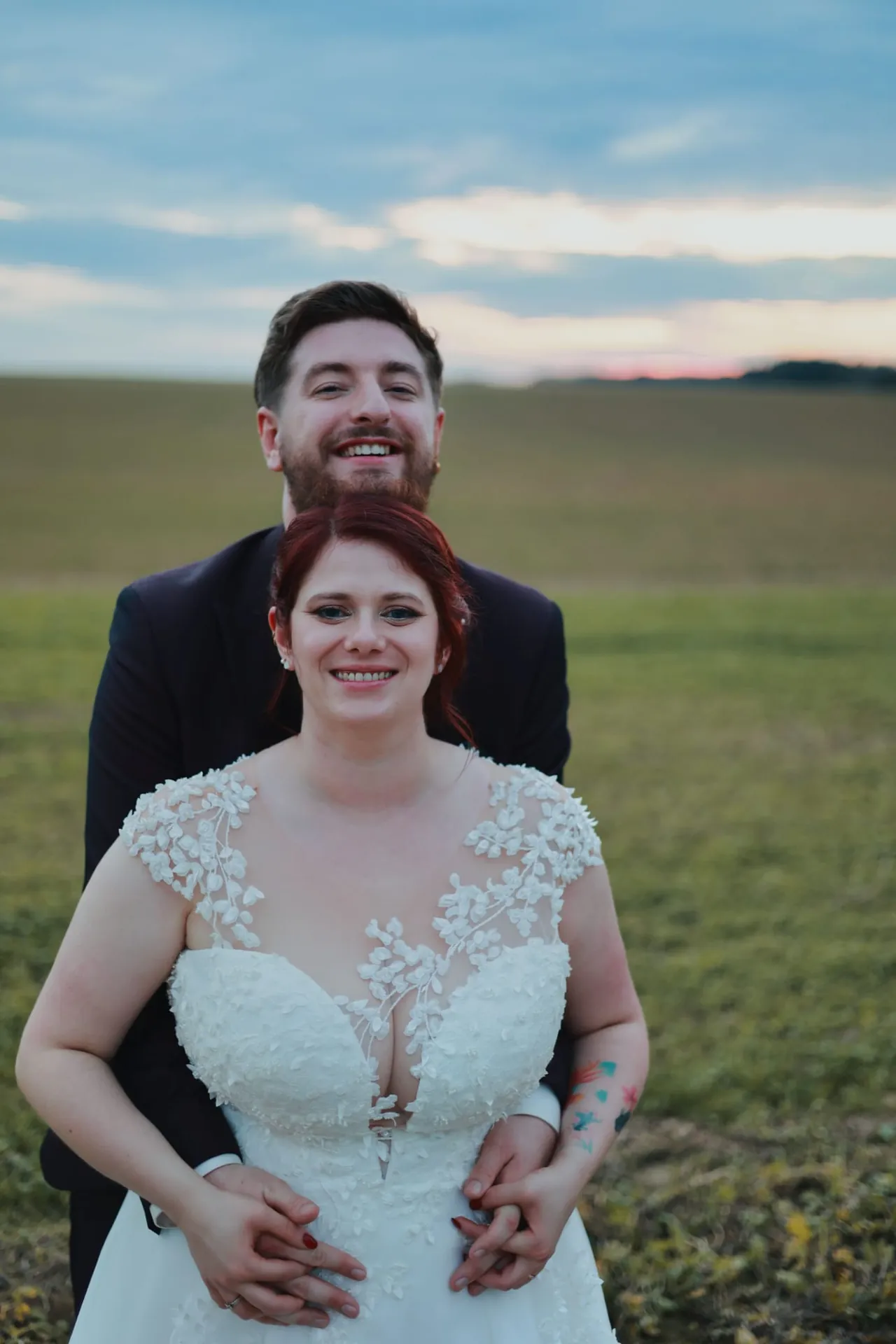 Le couple enlacé dans un champ, sous un ciel du soir