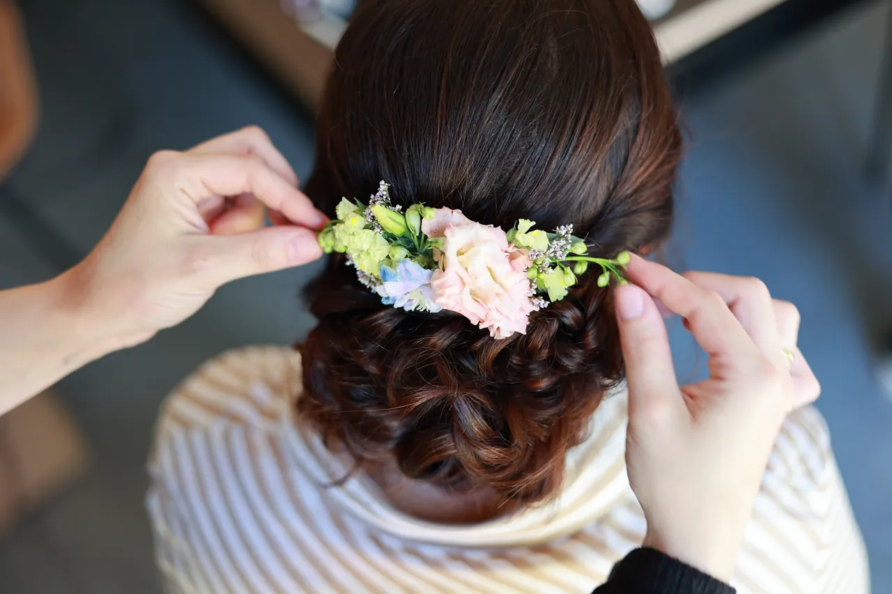 Des mains posent les fleurs dans le chignon