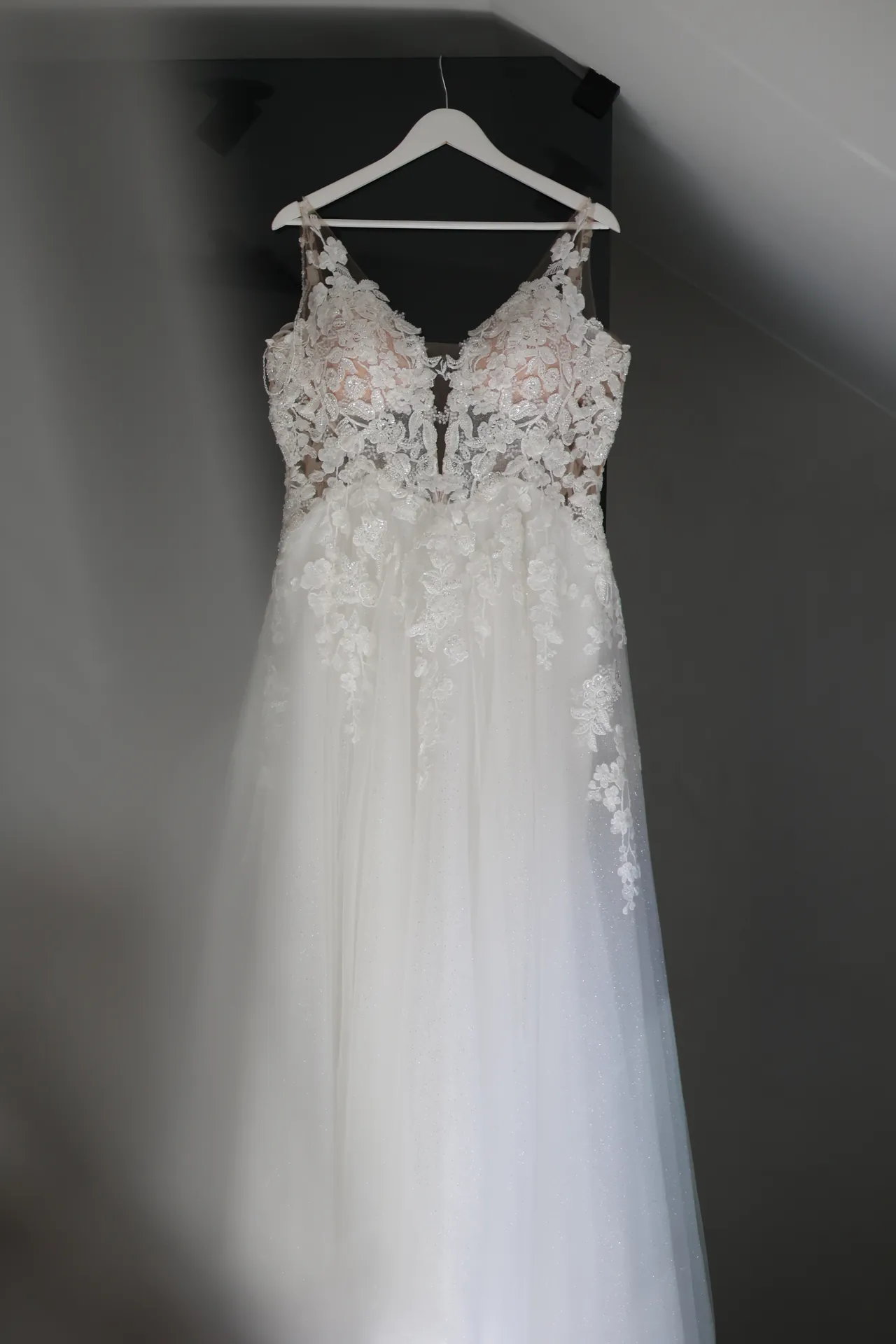 La robe en dentelle suspendue, dans la pénombre