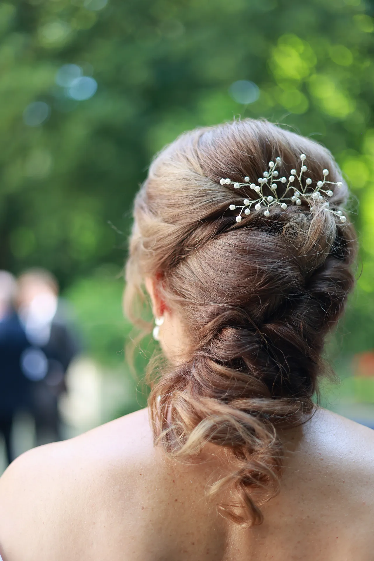 Un chignon piqué de perles, sur fond de verdure