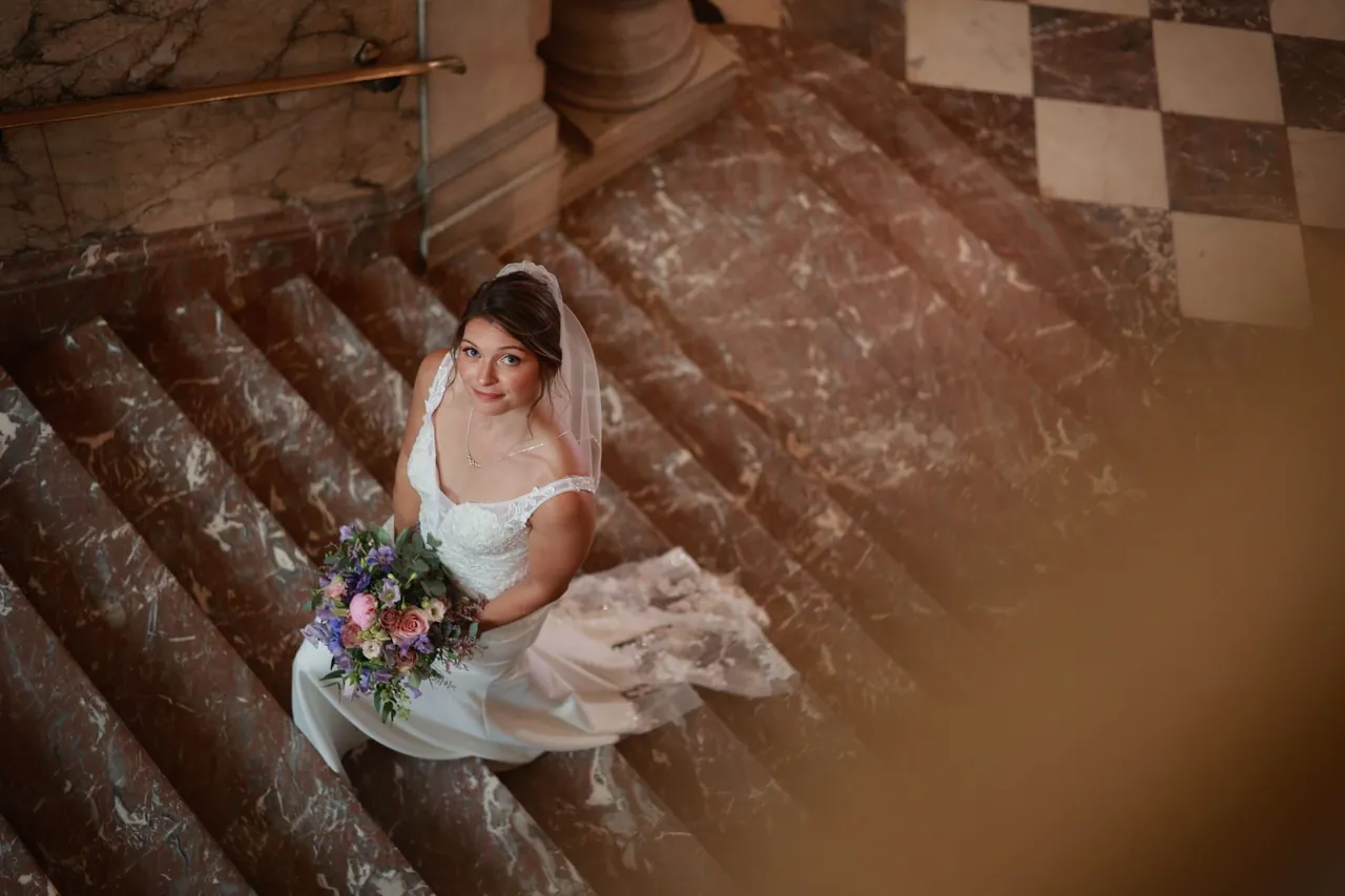 Portrait en plongée dans l'escalier de marbre, bouquet en main