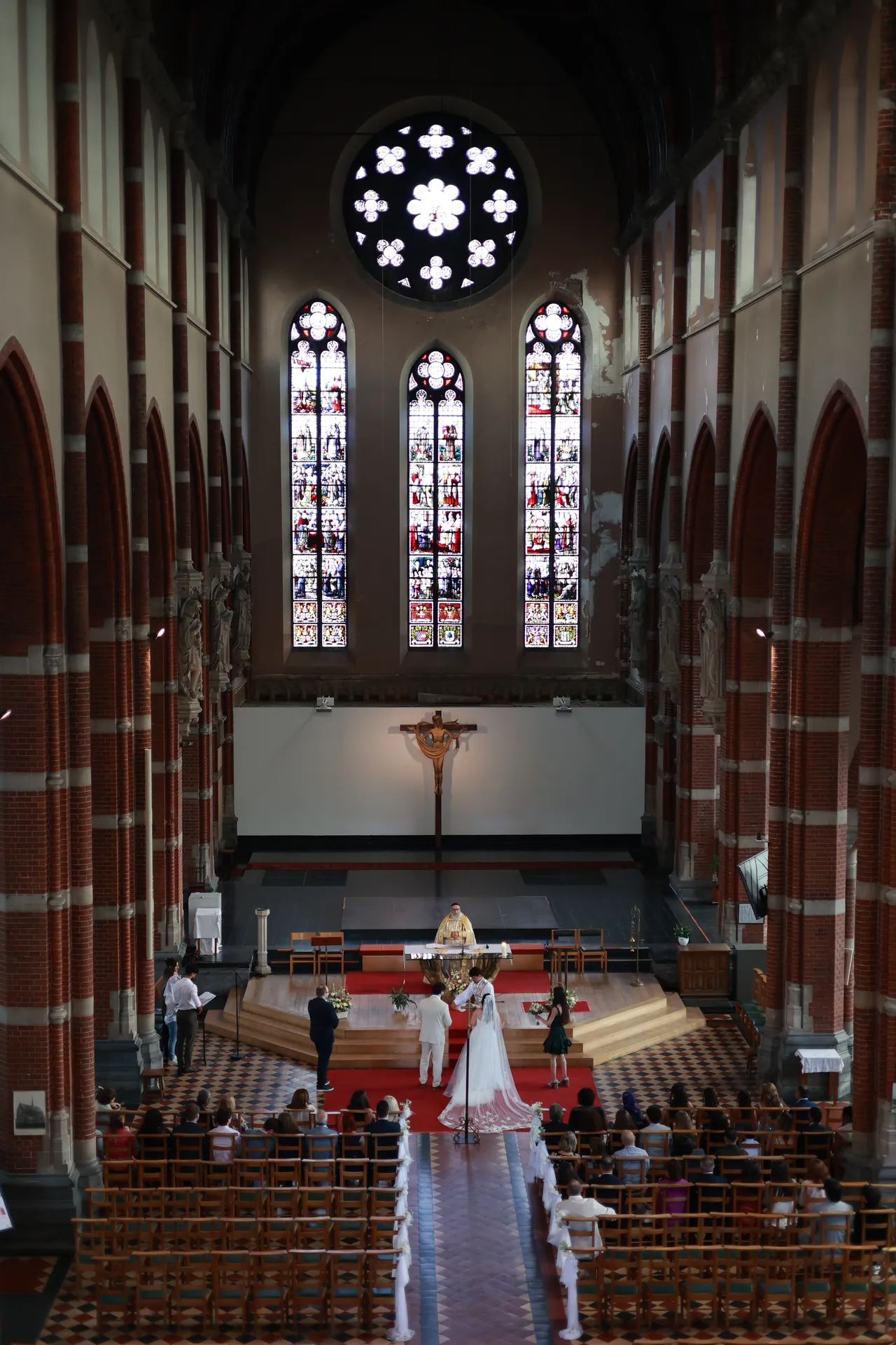Een bakstenen kerk gezien vanaf het oksaal, het roosvenster en de glasramen boven de ceremonie