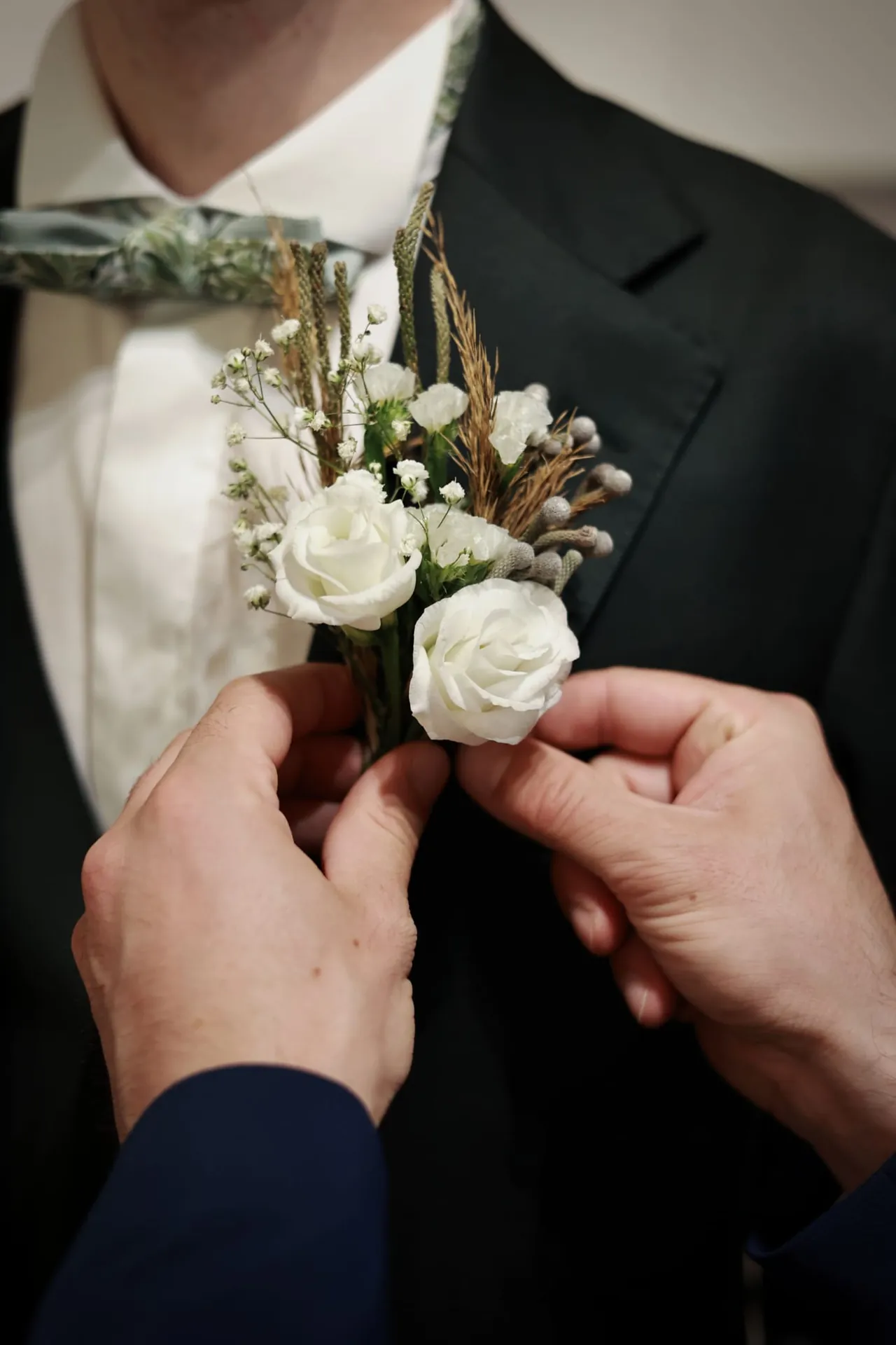 On épingle la boutonnière de roses blanches