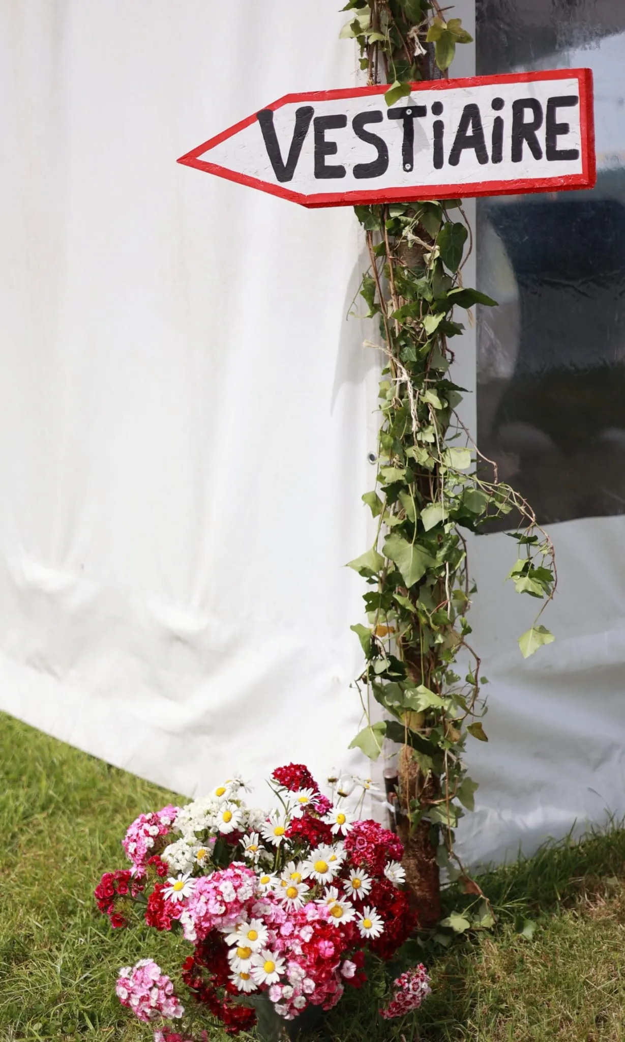 Le panneau « Vestiaire » et des fleurs au pied de la tente