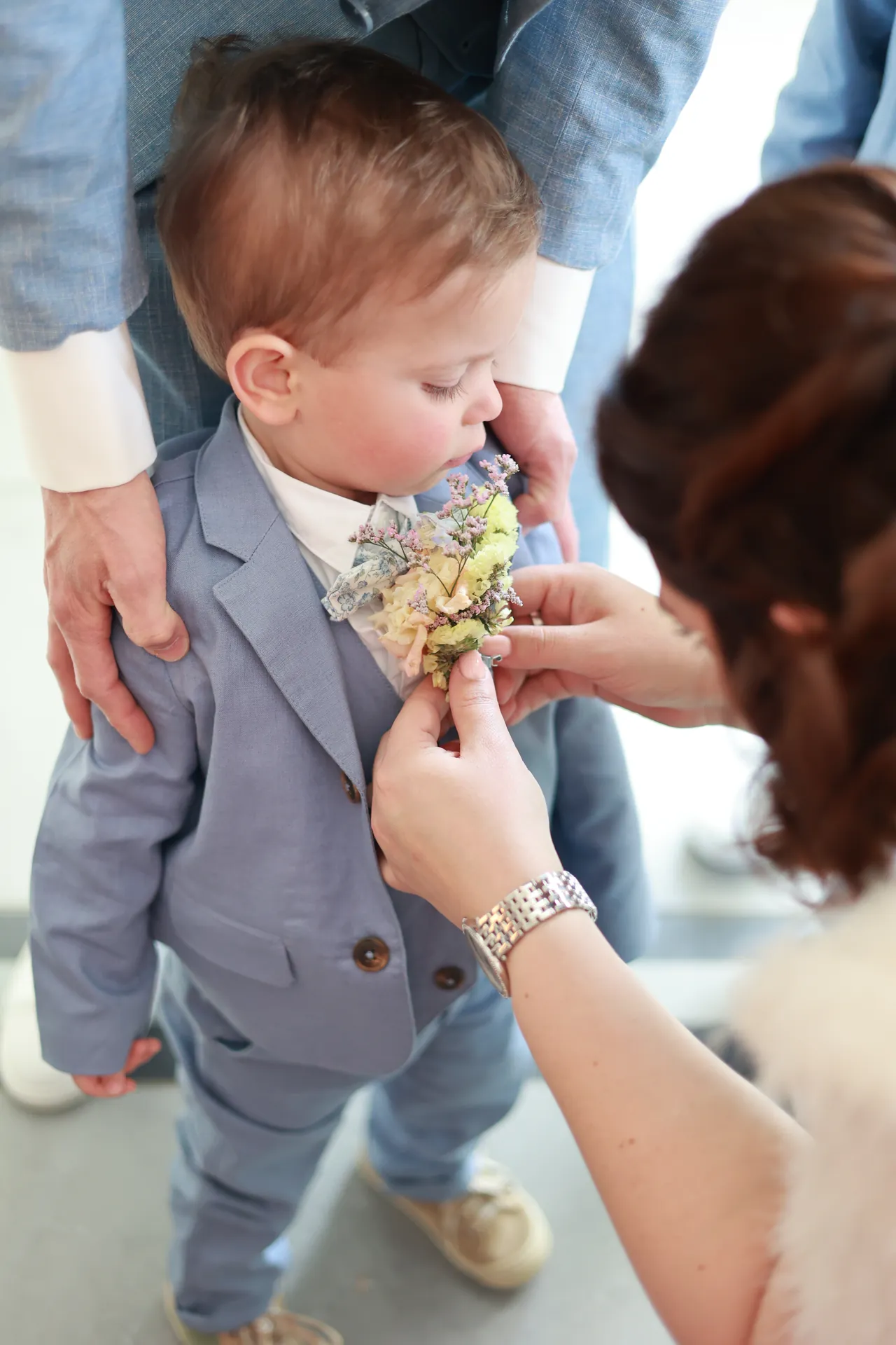 On épingle la boutonnière d'un enfant, qui sent les fleurs
