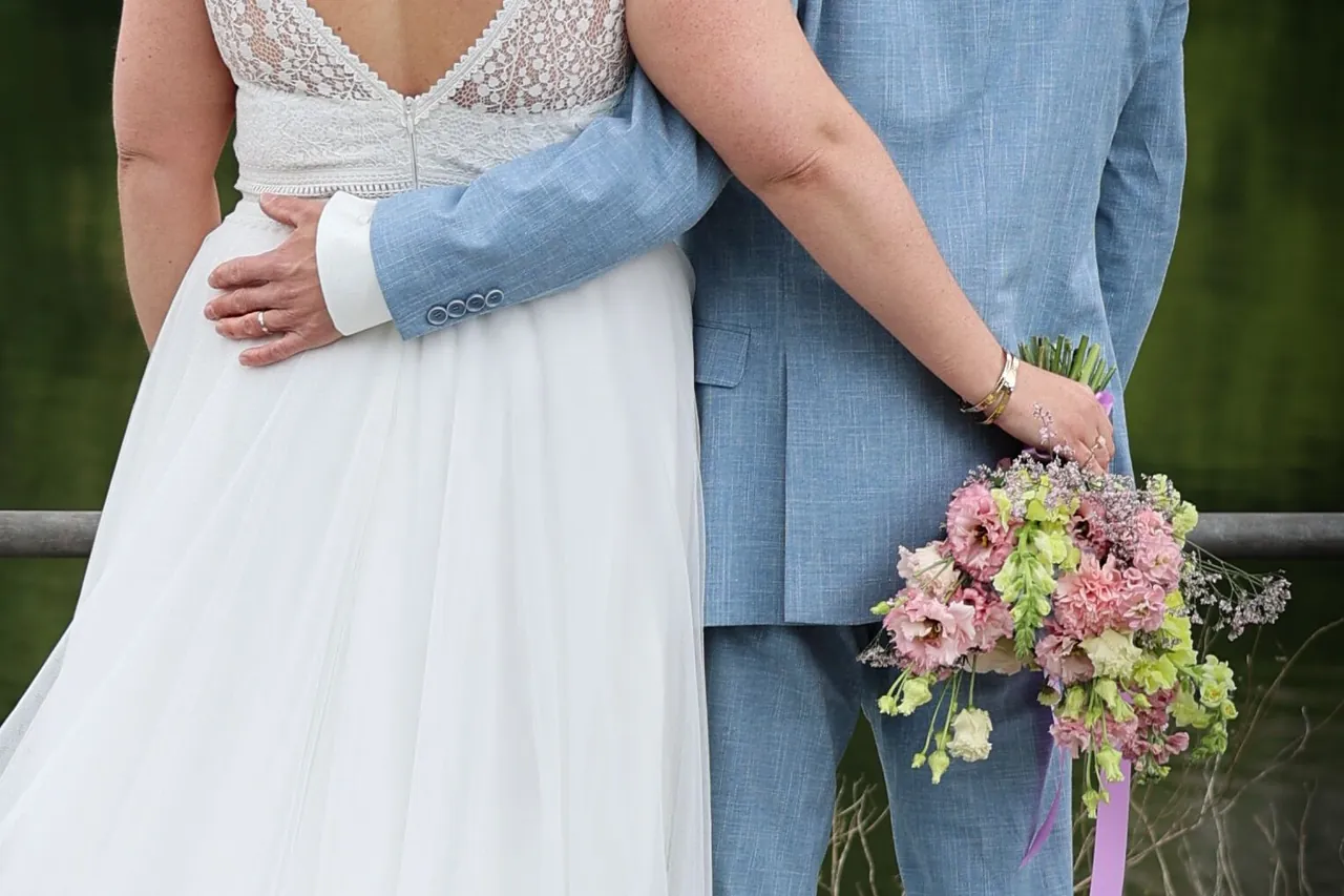 Une main sur la taille, le bouquet tenu dans le dos