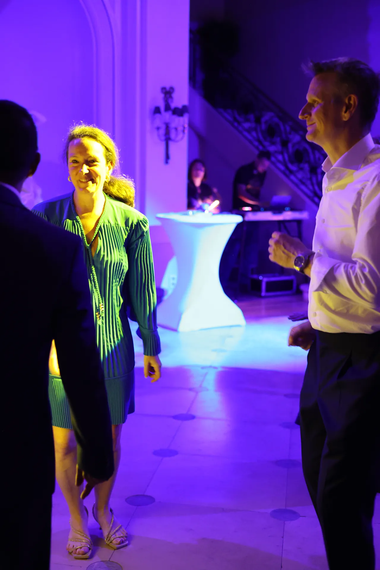 Een glimlach in een groene jurk op de dansvloer, in blauwachtig licht, de regie van de DJ op de achtergrond