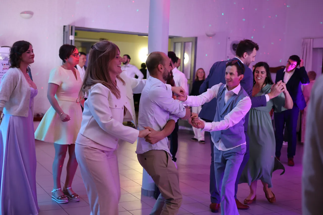 De volle dansvloer in paars licht, de gasten dansen lachend per twee