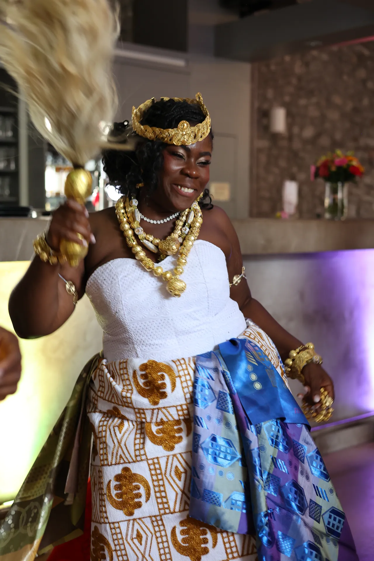 Traditionele kledij, kroon en gouden halskettingen: dansen met een glimlach, de vliegenwaaier omhoog