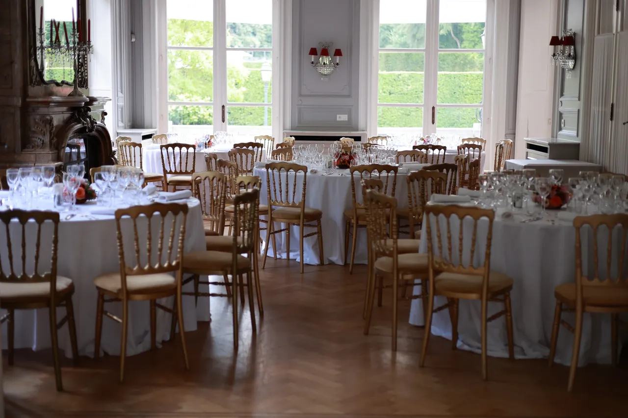 La salle dressée, chaises dorées et grandes fenêtres