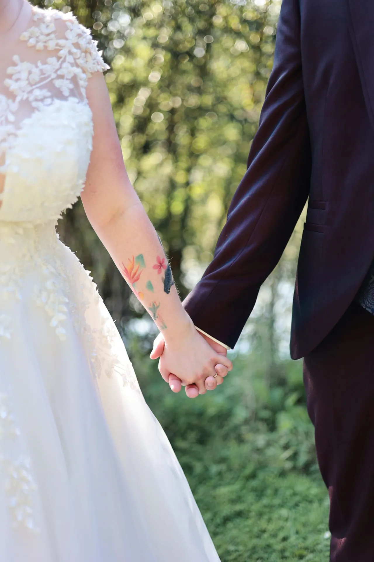 Les mains du couple entrelacées, sur fond de verdure