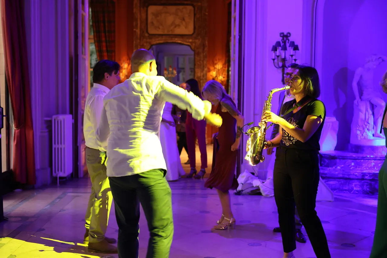 Saxofoon tussen de dansers, in een groot salon badend in paars licht