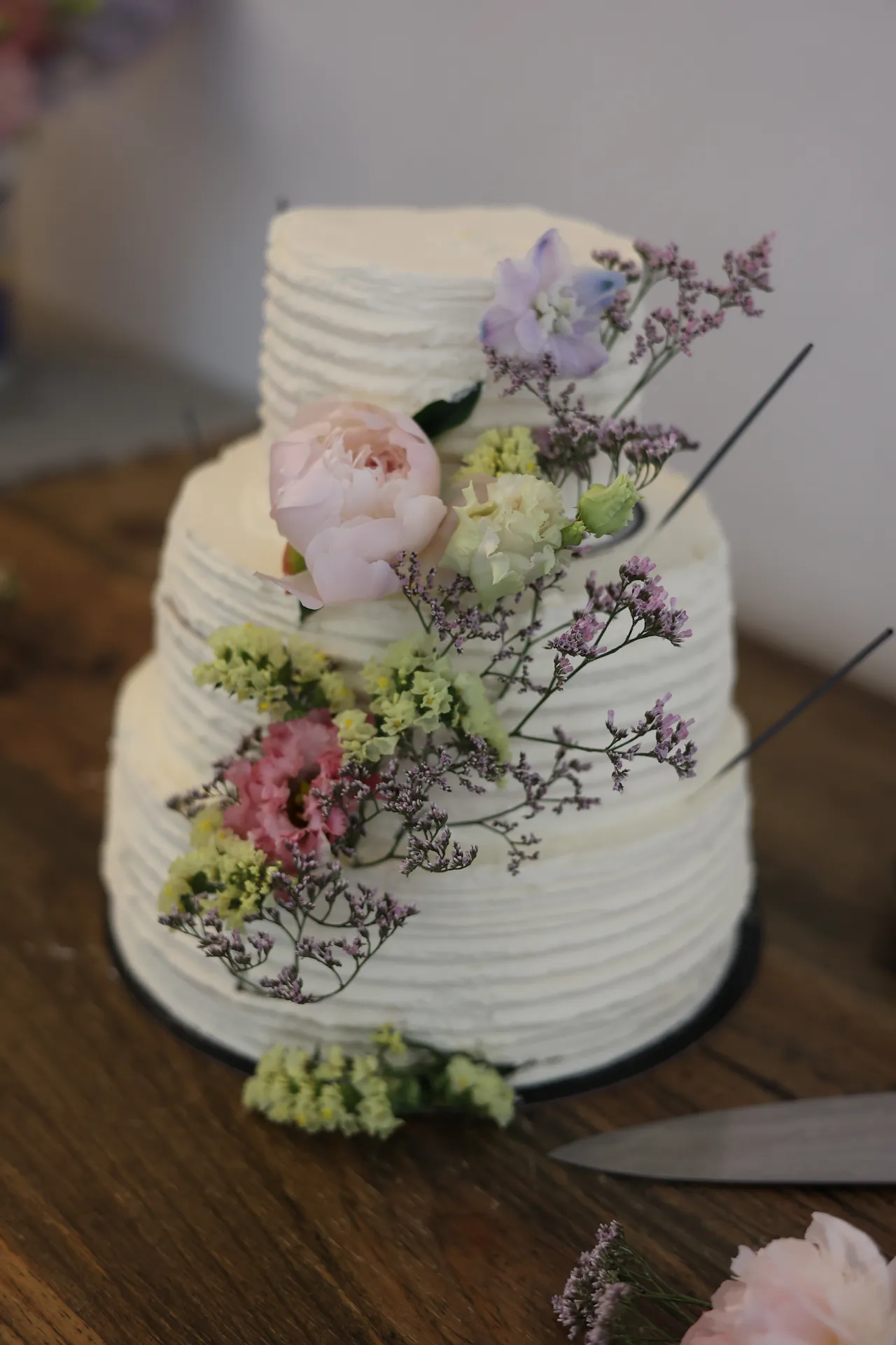 Een witte bruidstaart met drie verdiepingen, versierd met verse bloemen