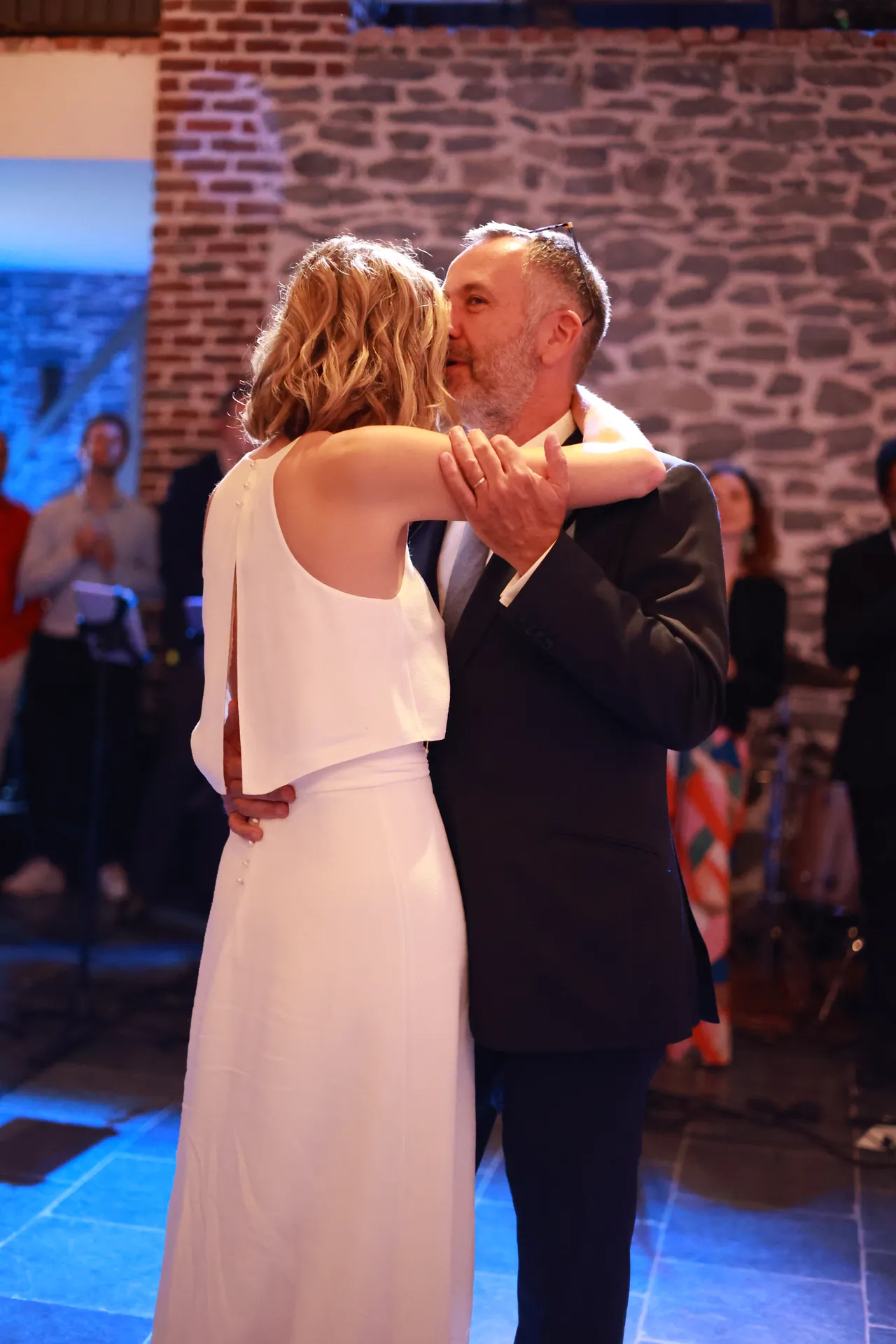 Het koppel danst in een omhelzing, een kus op de wang, voor een stenen muur