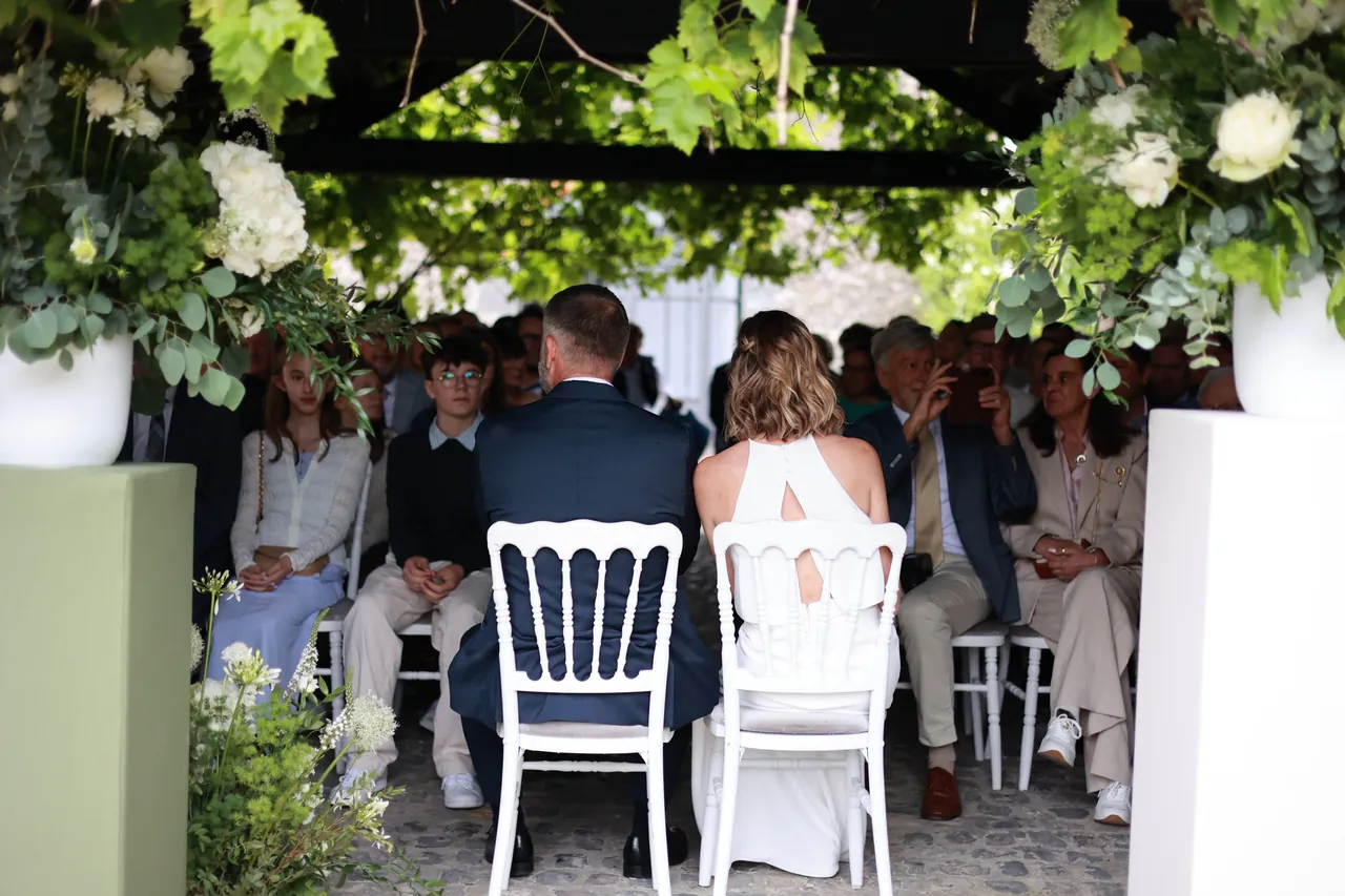 Assis sous la treille fleurie, face aux invités