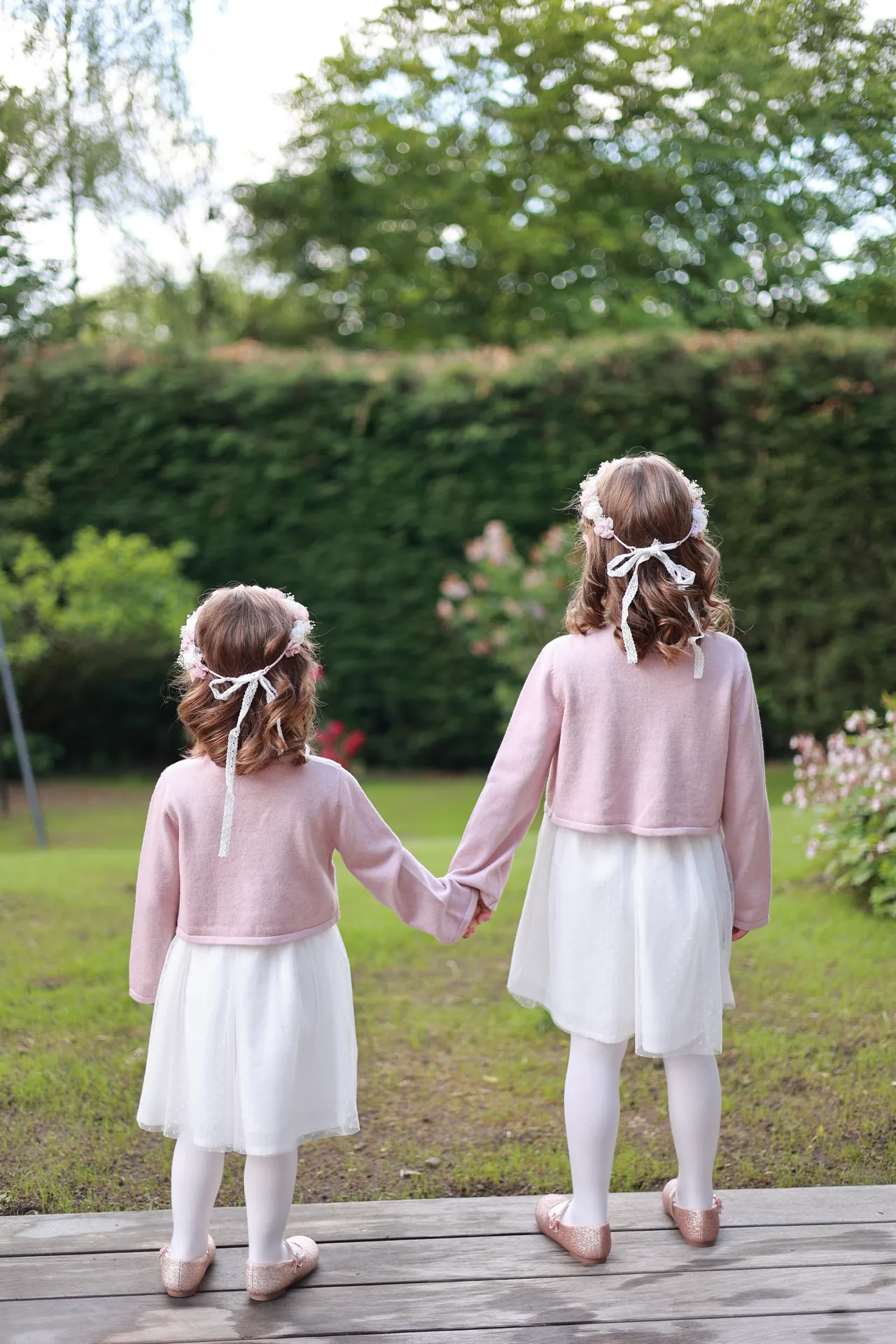 Deux enfants main dans la main, de dos dans le jardin