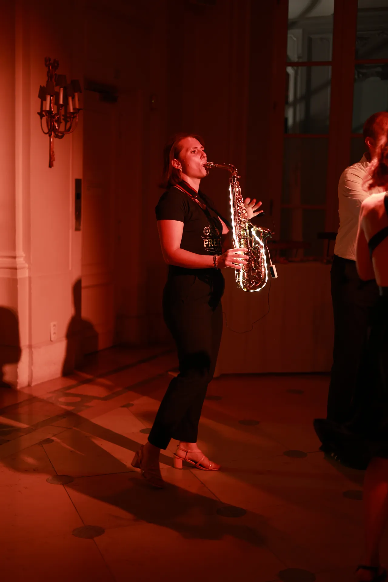 Saxofoonsolo in oranjerood licht, aan de rand van de dansvloer