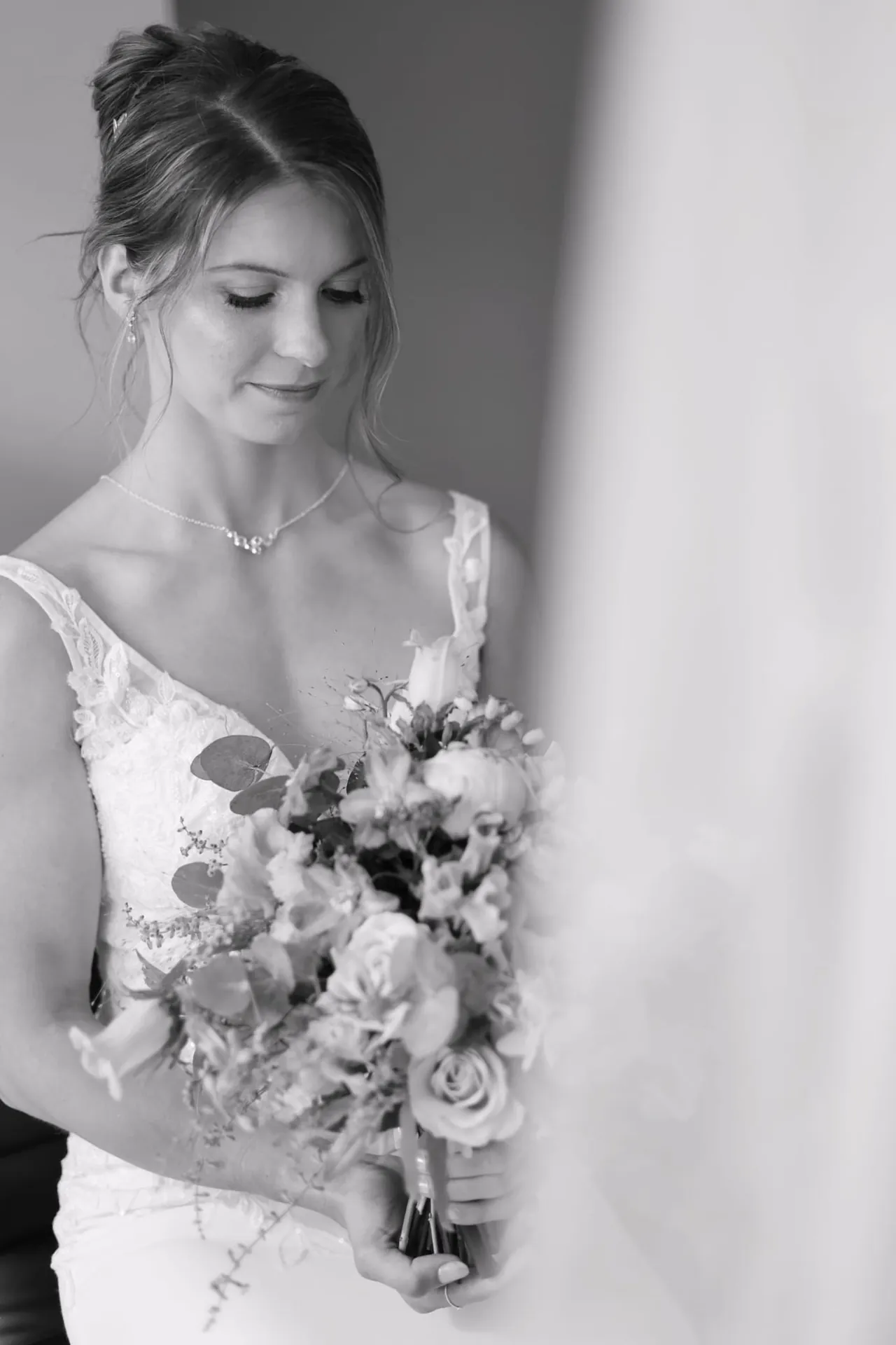 Le regard baissé vers le bouquet, en noir et blanc