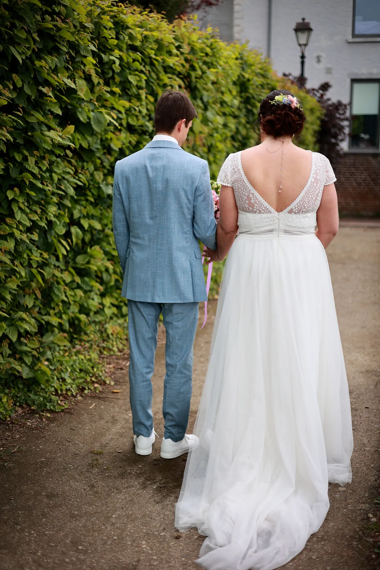 Le couple de dos, le long de la haie